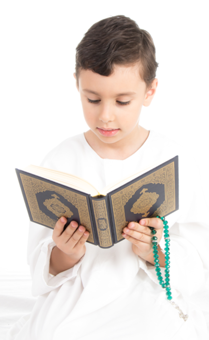 A little boy in white traditional clothing holdin Quran and having online Quran classes