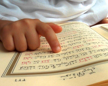 A young child reading the Quran, beginning their journey of memorization with dedication and focus.